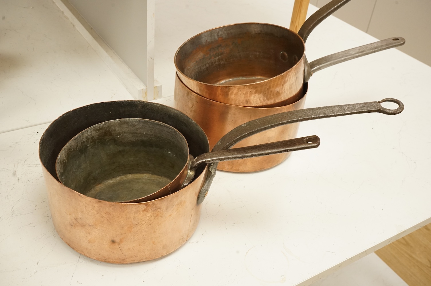 A graduated group of four large copper saucepans